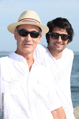 Foto: Father and son sat by waterfront Father and son sat by waterfront