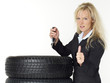 Woman next to winter tyres holding car key shows thumb up