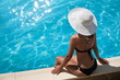 Foto: Young woman sitting on the ledge of the pool. Young woman sitting on the ledge of the pool.