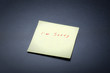 yellow postit with I'm sorry tect on a black board