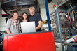 Smiling couple standing with mechanic using laptop