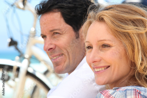 Photo: Headshot of couple with bikes by the sea Headshot of couple with bikes by the sea