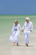 Happy Senior Couple Walking Holding Hands on a Tropical Beach