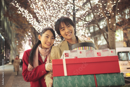 Photo: たくさん買ったプレゼントを持ちながら歩くカップル たくさん買ったプレゼントを持ちながら歩くカップル