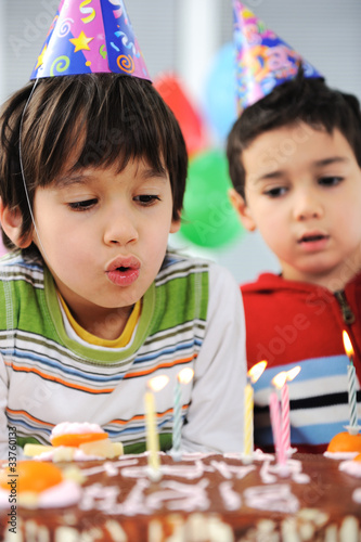Photo: Two little boys blowing candles on cake, happy birthday party Two little boys blowing candles on cake, happy birthday party