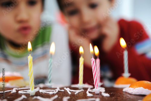 Photo: Two little boys blowing candles on cake, happy birthday party Two little boys blowing candles on cake, happy birthday party