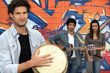 three musicians in front of a tagged wall