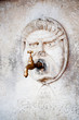 Photo: Brass water faucet and carved stone face on wall Brass water faucet and carved stone face on wall