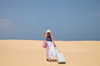 Foto: Woman walking with luggage on a sand to the sea Woman walking with luggage on a sand to the sea