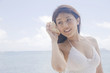 貝に耳を当てる女性