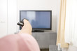 テレビをつける女性の後ろ姿