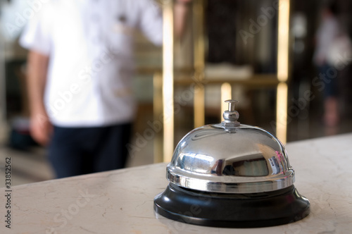 Photo: Hotel bell and bellboy at the background. Hotel bell and bellboy at the background.