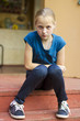 Little girl sits on the stair with resentful look