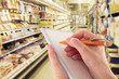Hand with Pen Writing a Shopping List in a Supermarket