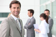 Smiling man with colleagues outside office building