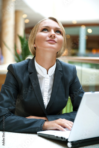 Photo: Portrait of a pretty businesswoman sitting at cafe with a laptop Portrait of a pretty businesswoman sitting at cafe with a laptop