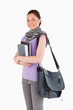 Beautiful student holding books and her bag while standing