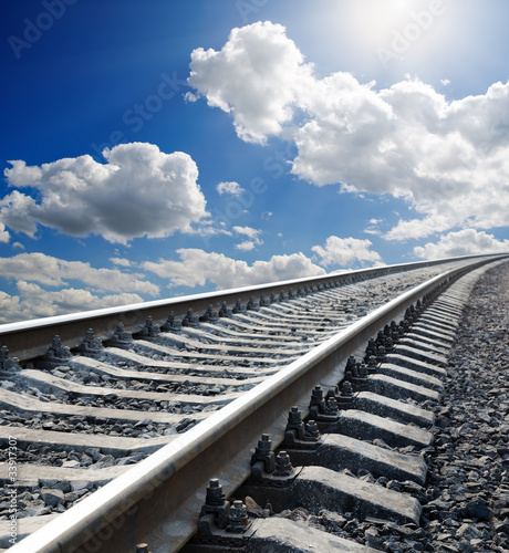 Photo: railway to horizon under cloudy sky with sun railway to horizon under cloudy sky with sun