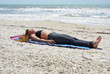 woman doing yoga exercise on beach in Savasana or corpse pose