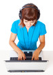 Red-haired teen-girl listen to music in headphones with laptop