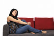 Foto: Junge Frau sitzt auf Sofa Junge Frau sitzt auf Sofa