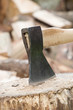 Axt in Hackklotz vor Haufen mit Holzscheiten