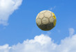 Photo: An old soccer (football) ball flies in a blue cloudy sky. An old soccer (football) ball flies in a blue cloudy sky.