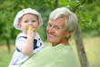 Foto: Child on grandmothers arm eating an apple Child on grandmothers arm eating an apple