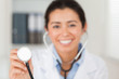 Attractive female doctor using a stethoscope while looking at th
