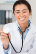 Pretty female doctor using a stethoscope while looking at the ca