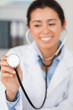 Gorgeous female doctor using a stethoscope while looking at the