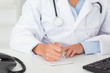 Female doctor with a stethoscope writing on a scratchpad