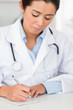 Beautiful female doctor writing on a scratchpad