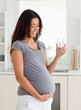 Charming pregnant woman holding a glass of water while standing