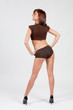 Jolie jeune femme mince posant sur fond blanc en boxer marron