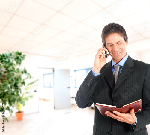 Foto: Businessman talking at the phone a looking at agenda Businessman talking at the phone a looking at agenda