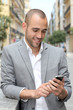 Relaxed businessman with mobile phone in town