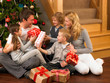 Photo: Family exchanging gifts in front of Christmas tree Family exchanging gifts in front of Christmas tree