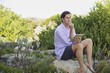 Man sitting on a rock using a digital tablet and thinking