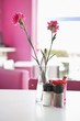 Vase with pink flowers and salt and pepper shakers on a table in a restaurant