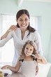 Portrait of a young woman and her daughter brushing teeth