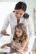 Mother applying tooth paste on little girls tooth brush at bathroom