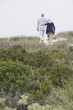 Rear view of a senior couple walking on the beach with their arms around each other
