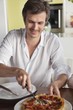 Man cutting pizza at a dining table