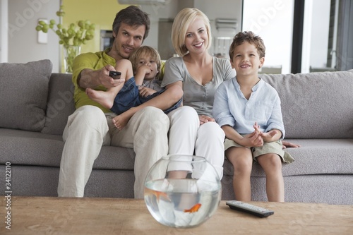 Photo: Couple watching television with their sons Couple watching television with their sons