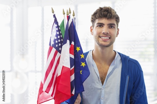 Photo: Portrait of a man holding flags of various countries at an airport Portrait of a man holding flags of various countries at an airport