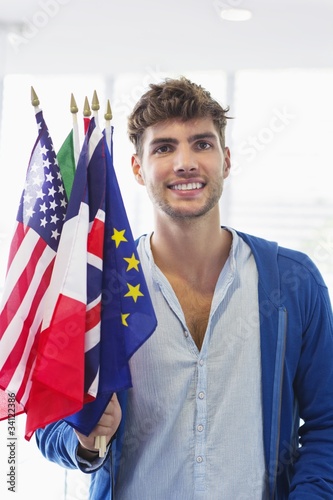Photo: Portrait of a man holding flags of various countries at an airport Portrait of a man holding flags of various countries at an airport