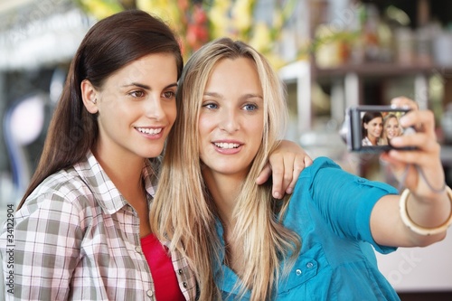 Photo: Female friends taking a picture of themselves with a camera Female friends taking a picture of themselves with a camera