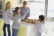 Couple with their two children preparing food at a domestic kitchen
