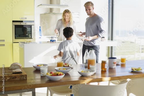 Photo: Couple with their son preparing food in a domestic kitchen Couple with their son preparing food in a domestic kitchen